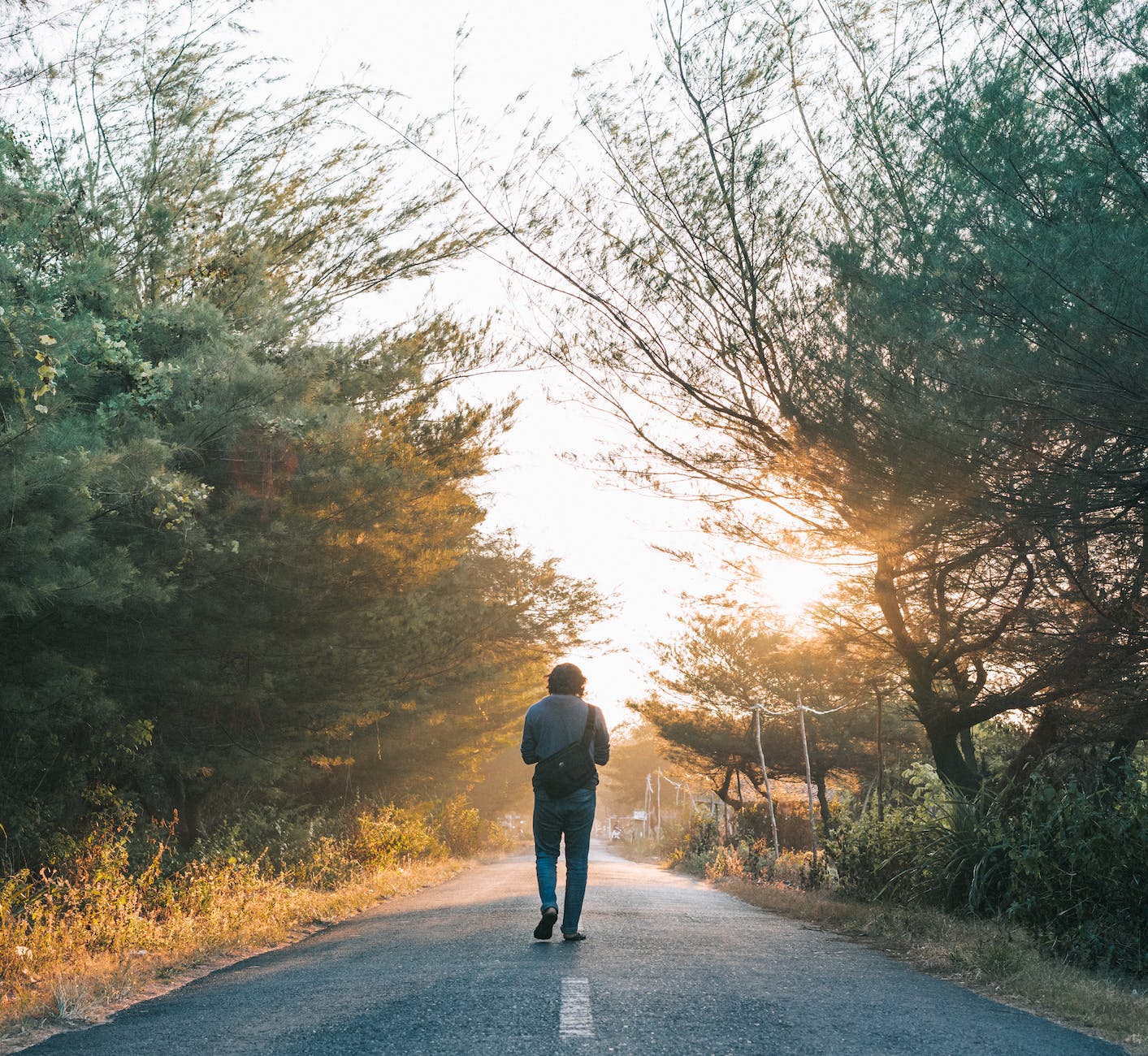 man walking on the gray asphalt road